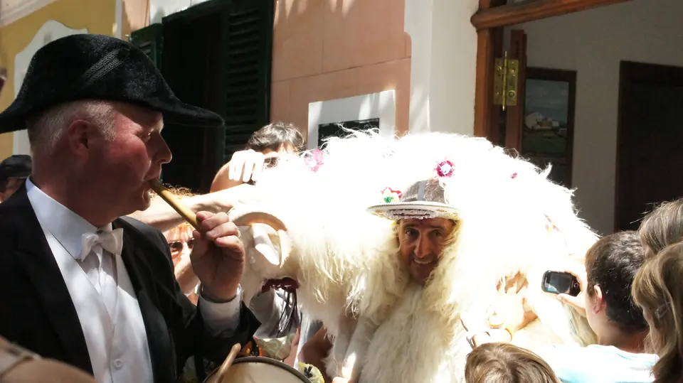 Homme en costume traditionnel et bonnet de fourrure à côté d’un autre personnage de la fête