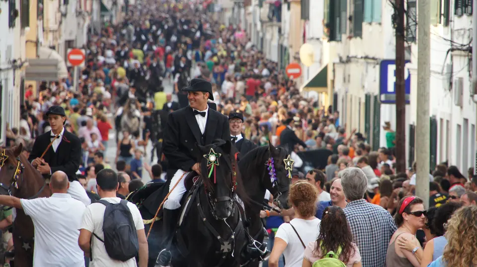 Foule dans une rue avec des cavaliers à cheval pendant une fête