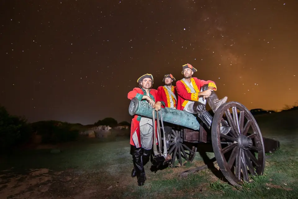 Figurants en uniforme militaire d’époque près d’un canon sous un ciel étoilé