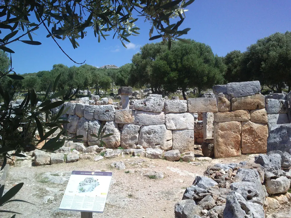 Mur de grans blocs de pedra a Torre d’en Galmés, amb un panell informatiu