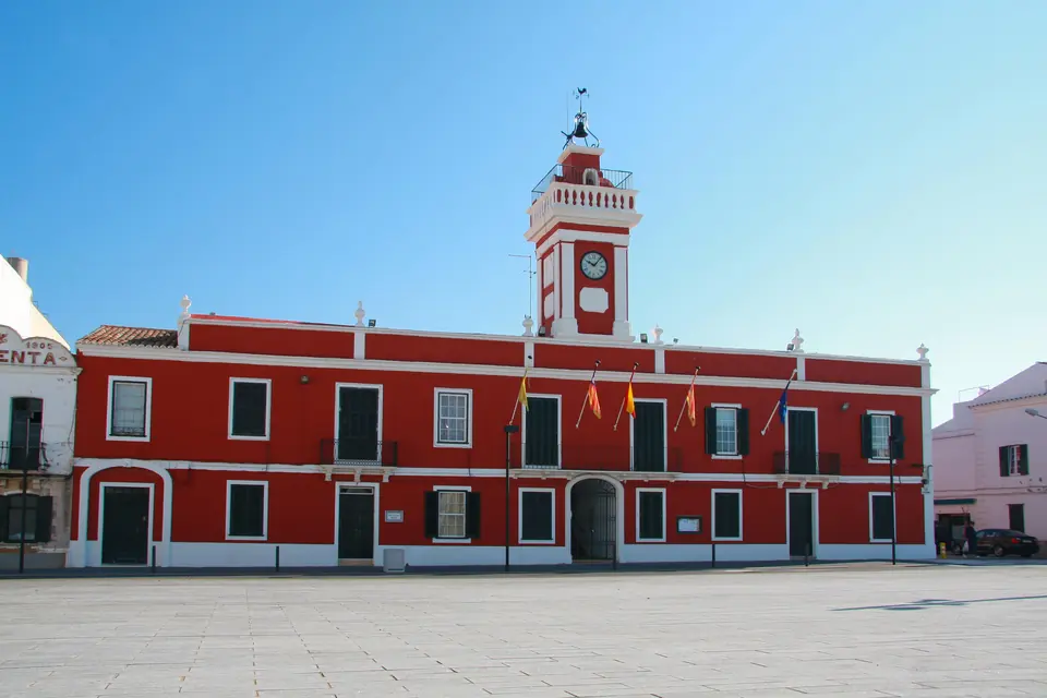 Ajuntament de façana vermella amb torre del rellotge en una plaça