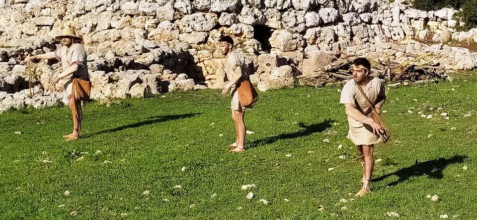 Personnes en tenue préhistorique devant un mur de pierre