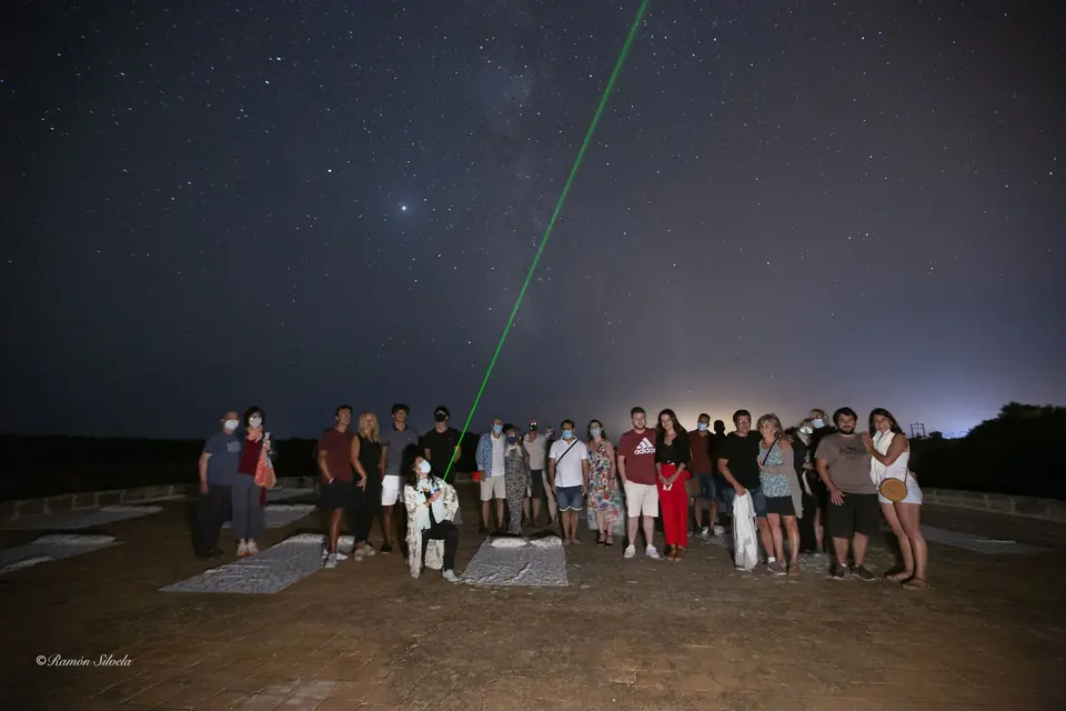 Gruppo di persone che osserva il cielo notturno con un puntatore laser verde